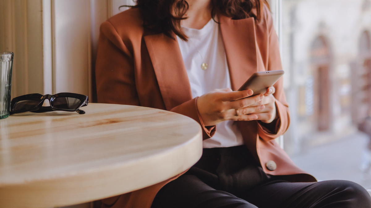 Woman sitting at table using SMS on smartphone